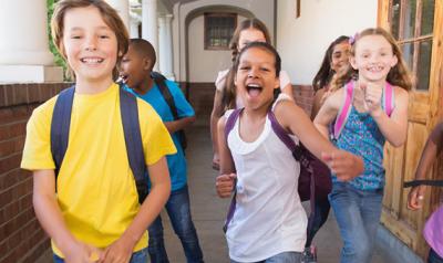 Children wearing backpacks in school hallway