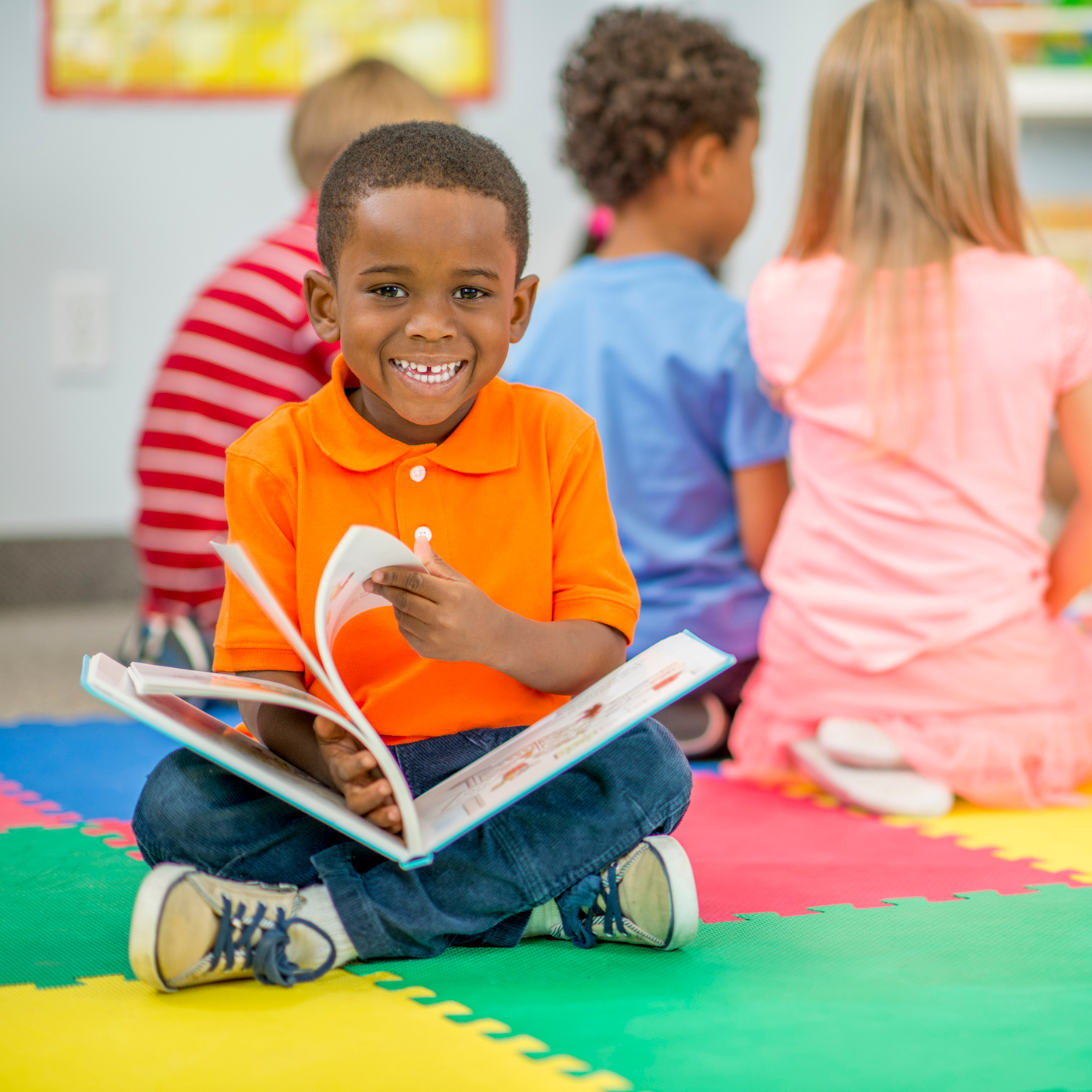 Preschooler reading a book in the classroom.