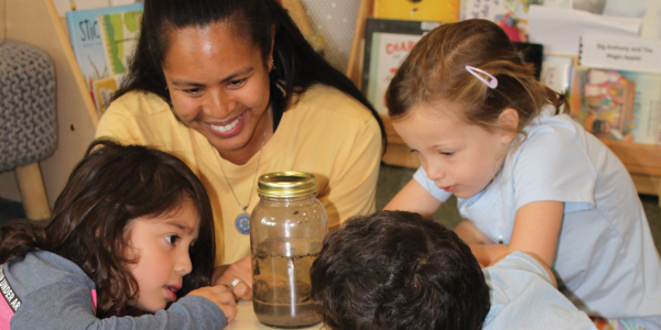 a teacher with a group of children looking in a jar